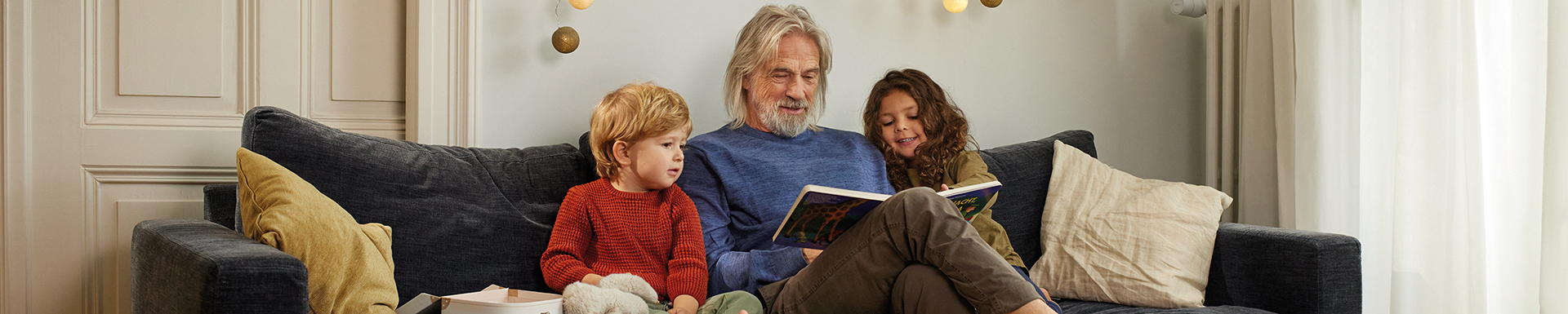 Ein Großvater ließt den Kinder eine Geschichte vor.