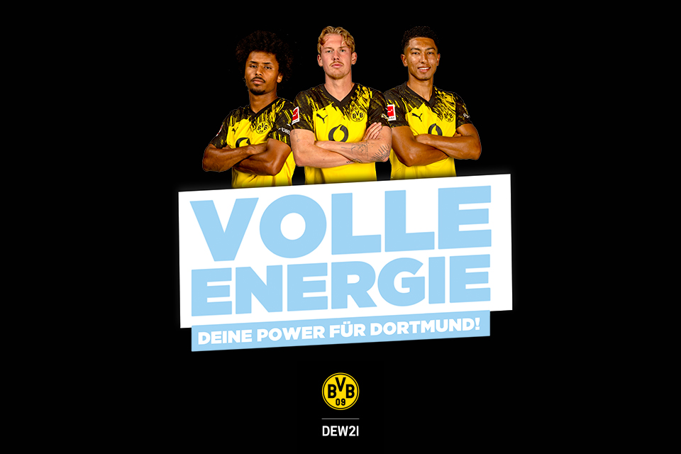 Drei BVB-Spieler in gelben Trikots vor Schild „Volle Energie für Dortmund“