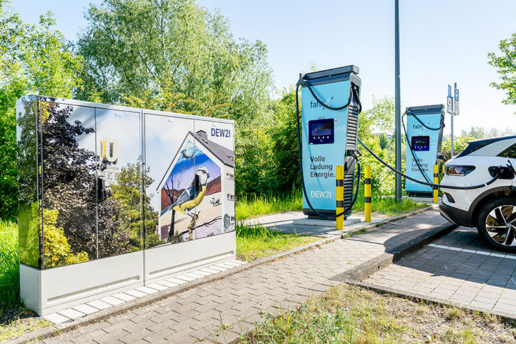 Stromkasten mit Vogelmotiv neben Ladesäulee für e-auto