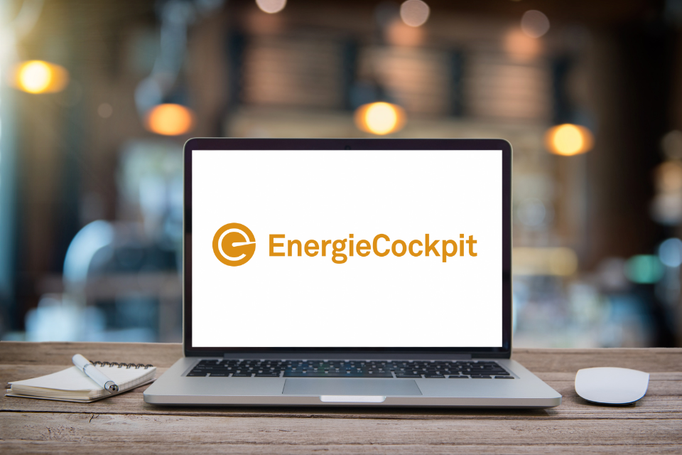 Laptop mit 'EnergieCockpit'-Anzeige, daneben Notizblock und Stift.