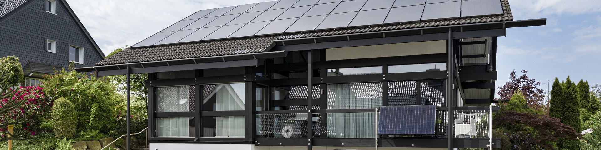 Modernes Haus mit Solardach, Balkonkraftwerk und Garten, nachhaltige Architektur im Wohngebiet