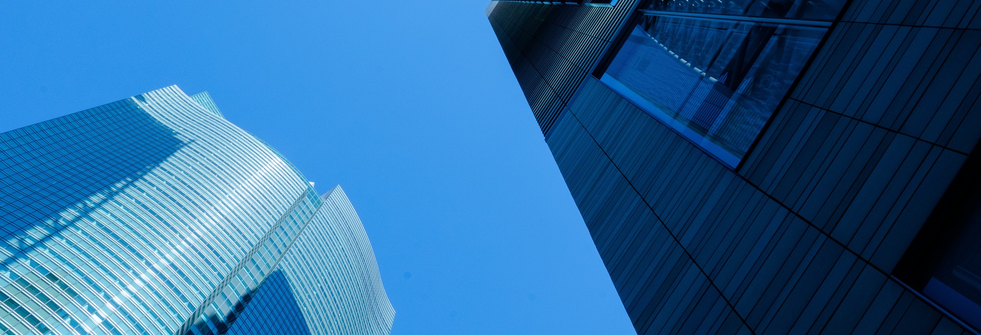 Moderne Wolkenkratzer mit Glas- und Stahlfassaden vor klarem Himmel.