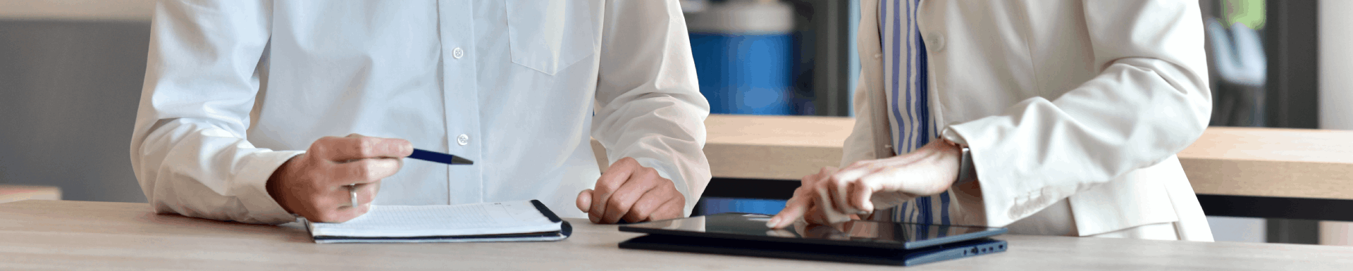 zwei Menschen stehen an einem Tisch und tippen auf einem Ipad