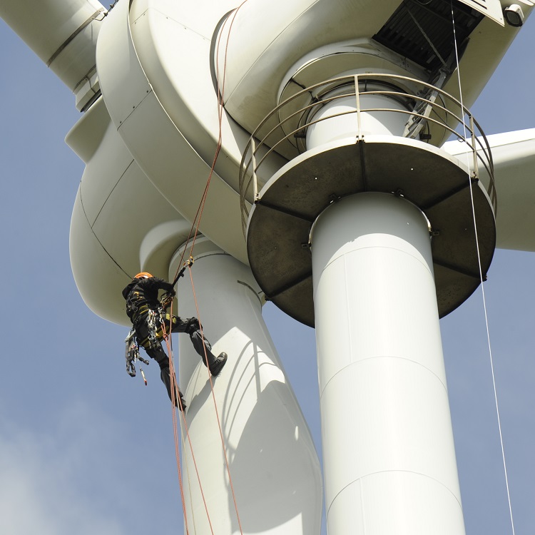 Zwei Personen in Sicherheitsausrüstung warten Windturbine, aufgehängt an Seilen.