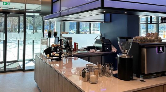 Innenansicht eines modernen Cafés mit Theke, Espressomaschine und Gebäckauslage.