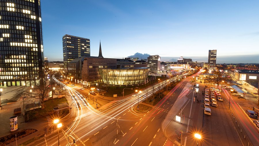 Nächtliche Stadtansicht von Dortmund mit Lichtspuren von Autos und beleuchteten modernen Gebäuden