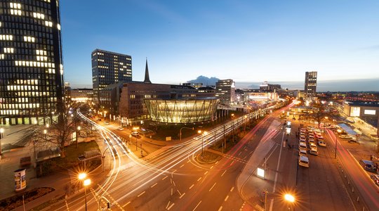Nächtliche Stadtansicht von Dortmund mit Lichtspuren von Autos und beleuchteten modernen Gebäuden