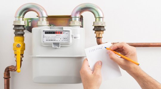 Gaszähler mit Händen die den Zählerstand notieren