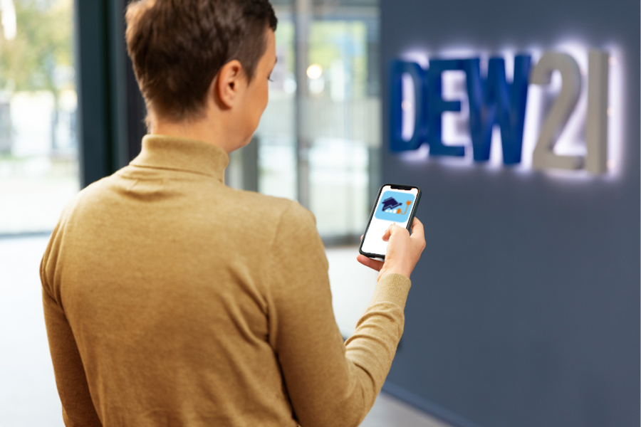 Frau die Handy mit App Symbol von DEW21Energycontroll in der Hand hält