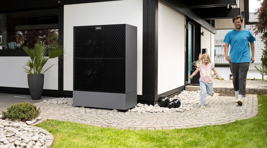 Kraft-Wärme-Kopplung Modernes Haus mit Viessmann-Einheit, daneben ein Erwachsener und ein Kind auf einem Weg.