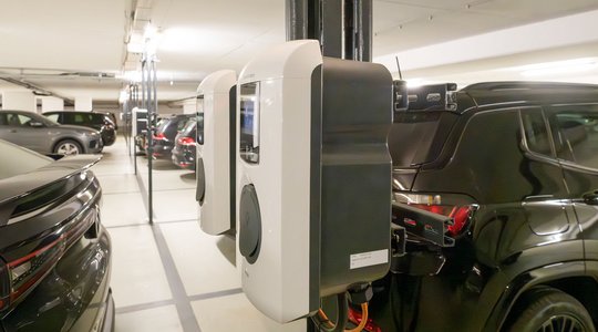 Zwei E-Ladestationen an einer Säule in Tiefgarage mit mehreren geparkten Autos