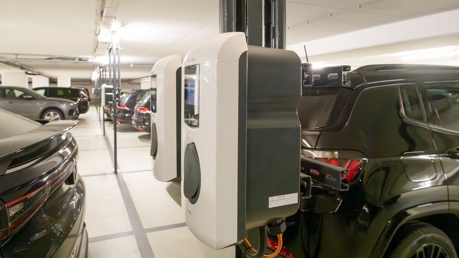 Zwei E-Ladestationen an einer Säule in Tiefgarage mit mehreren geparkten Autos
