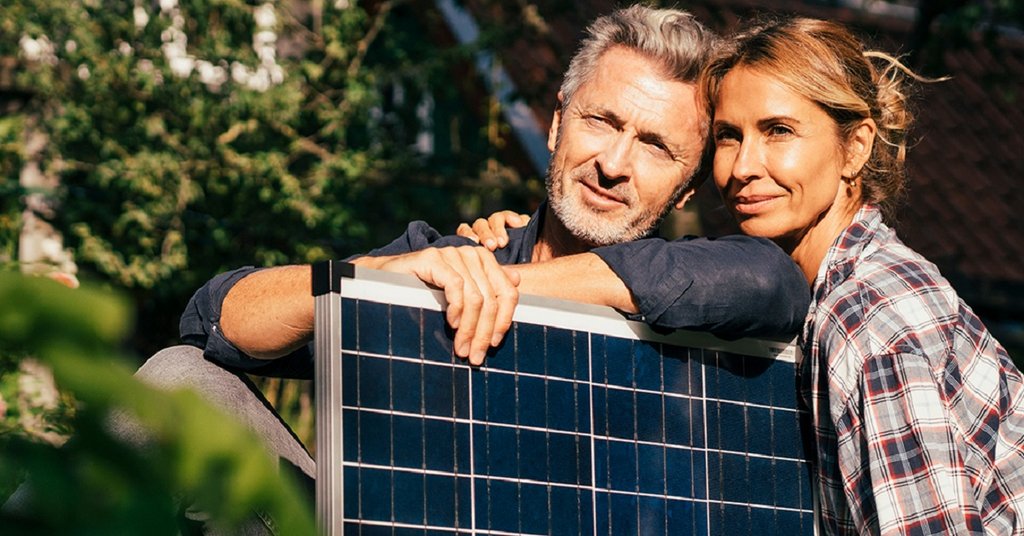 Ein Paar hält ein Solarmodul für ihren Balkon fest.