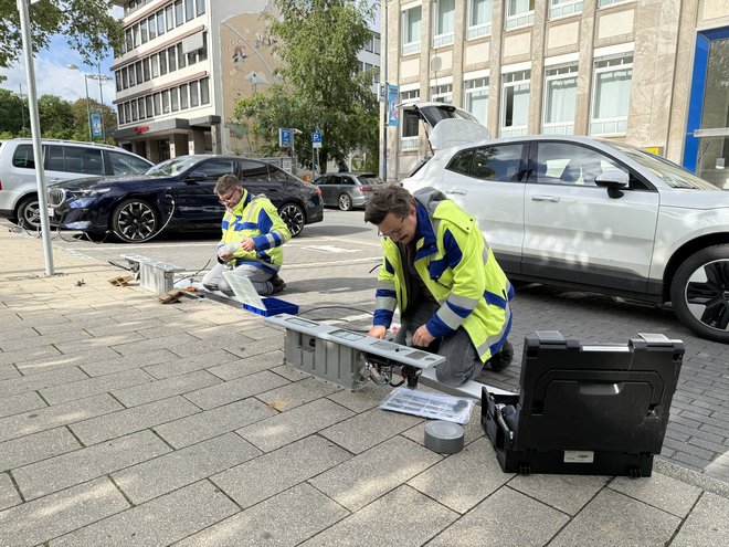 Zwei Techniker von DEW21 installieren Ladebordsteine auf Parkflächen