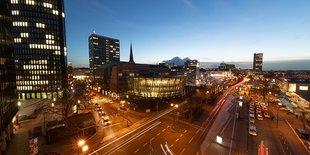 Stadtlandschaft bei Dämmerung, Gebäude, Straßen und Lichtspuren von Fahrzeugen.