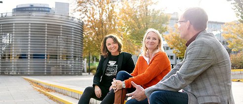 Gruppe von drei Menschen auf einer Treppe sitzen am Friedensplatz in Dortmund
