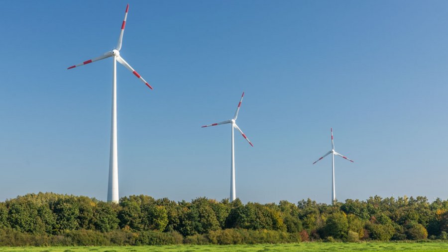 drei Windräder auf einer grünen Wiese