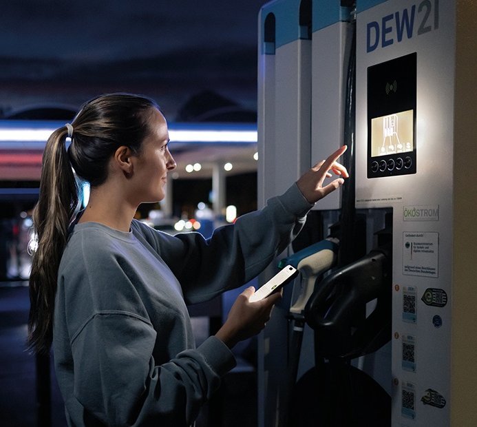Eine Frau steht an einer DEW21 Ladesäule.