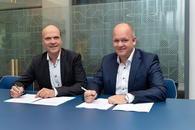 Foto von Peter Flosbach, Technischer Geschäftsführer bei DEW21, und Dominik Serfling, Leiter Stadtentwicklungsprojekte bei DSW21, die am Tisch sitzend Verträge unterzeichnen