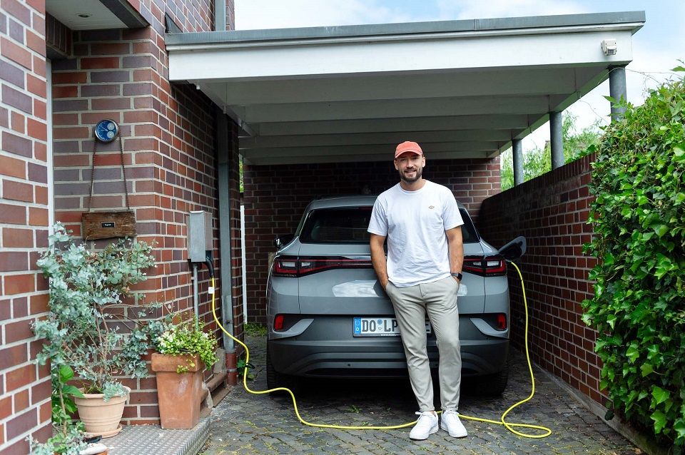 Ein Mann steht vor seinem Elektroauto.