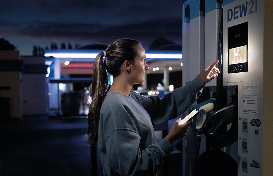 Eine Frau steht an einer Ladesäule für Elektroautos.